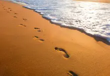 bigstock-beach-wave-and-footsteps-at-s-38822107resized